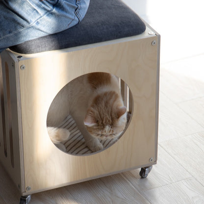 Person seated on the CheerMoe Haven Cat House Stool with a cat inside the round entrance