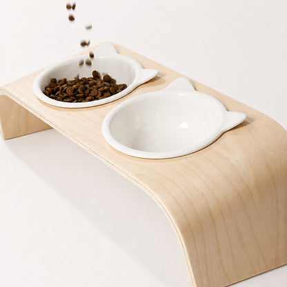 Dry cat food being poured into one of the raised ceramic bowls