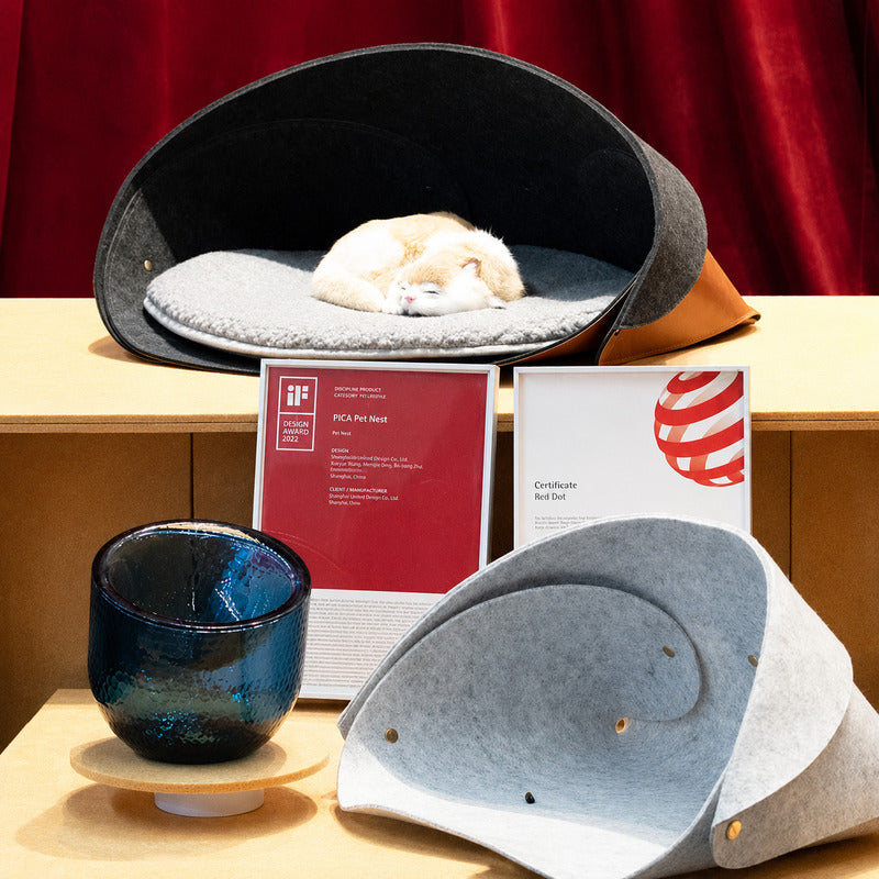 Pica foldable pet nest display with a sleeping cat and Red Dot and iF Design Award certificates